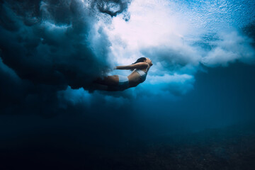Woman swim underwater with breaking wave with foam in transparent ocean. - obrazy, fototapety, plakaty