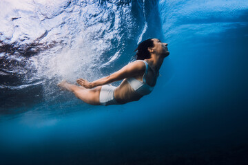 Woman dive without surfboard with ocean wave. Duck dive under barrel wave