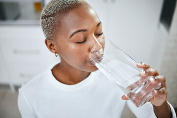 Health, glass and woman drinking water for hydration, wellness and liquid nutrition at her home....