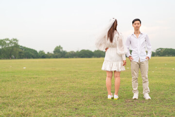 Naklejka na ściany i meble Happy young Asian couple in bride and groom clothing
