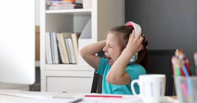 Little girl with headphones listening to music and singing at computer 4k movie. Entertainment for children concept