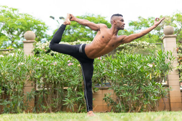 Black calm man doing yoga in Dancer Pose