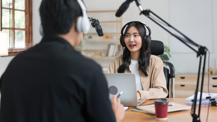 Young women using laptop and microphone to interviewing man guest and recording for audio podcast