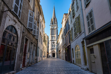 Obraz premium Narrow alley with picturesque streets and old church in the background illuminated by the sun, Pau, France.