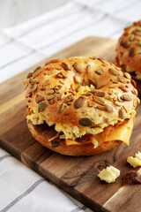 Homemade Bacon, Egg & Cheese Bagel Breakfast Sandwich on a wooden board, side view. Copy space.
