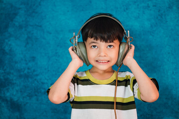 Young asian boy wearing headset listening music isolated on gray background. Melody,sound and music concept