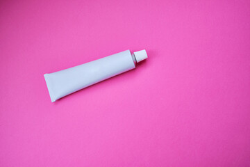 Stylish metal tube for drug or cosmetic branding - cream, gel, skin care, toothpaste. Container for cosmetic bottles on a colored background. Minimalism