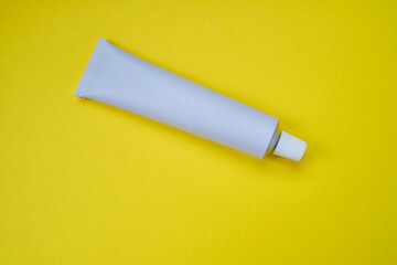 Stylish metal tube for drug or cosmetic branding - cream, gel, skin care, toothpaste. Container for cosmetic bottles on a colored background. Minimalism