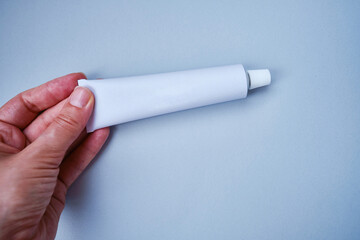 Stylish metal tube for drug or cosmetic branding - cream, gel, skin care, toothpaste. Container for cosmetic bottles in the hands of a girl. Minimalism