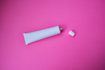 Stylish metal tube for drug or cosmetic branding - cream, gel, skin care, toothpaste. Container for cosmetic bottles on a colored background. Minimalism