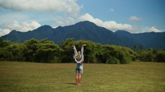Tourist Woman at the mountains, freedom. Happy girl relaxing and doing yoga on the field with mountain view. 