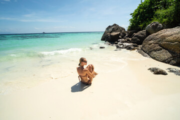 Fototapeta na wymiar Beautiful woman sunbathing and relaxing at amazing tropical beach in a sunny summer day. Koh Lipe island