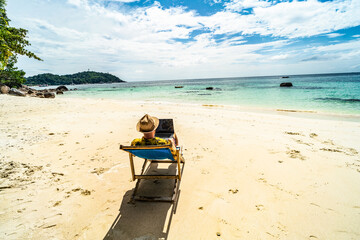 Man in the summer hat , a businessman, digital nomad working with laptop on the tropical beach. Freelancer lifestyle
