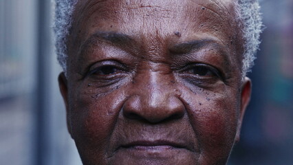 Dramatic macro close-up of a senior black woman looking at camera with serious expression. Portrait of a South American elderly lady