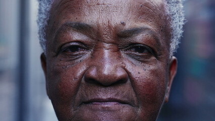 Dramatic macro close-up of a senior black woman looking at camera with serious expression. Portrait of a South American elderly lady