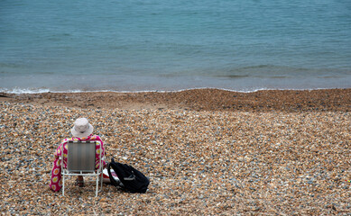 Senior woman relaxing on a pebble beach. Summer holidays people leisure time