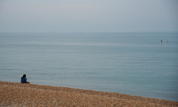 Person relaxing on a pebble beach. Summer holidays people leisure time - Powered by Adobe