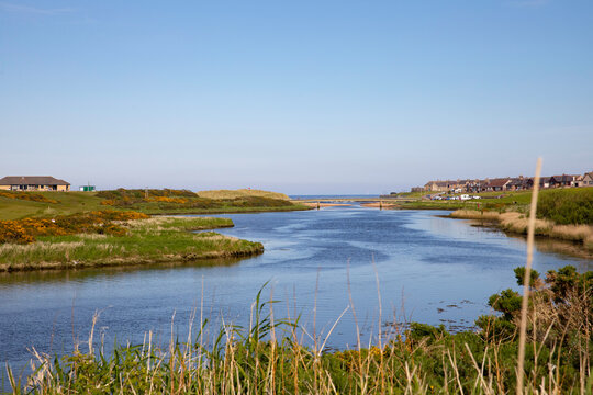 The river Ugie looking towards the town of Peterhead and the village of Buchanhaven on the right with the golf club and golf course on the left. A bridge and the sea are in the distance.