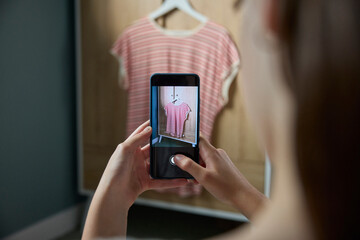 Teenage Girl Taking Photo Of Clothing On Mobile Phone To Sell Online