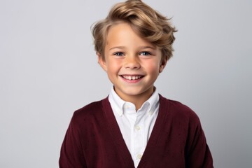 Portrait of a cute little boy smiling at the camera while standing against grey background