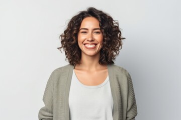 portrait of smiling young woman with curly hair looking at camera isolated on grey