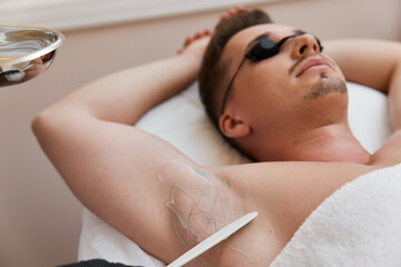 young man undergoes procedure of arm pit laser epilation