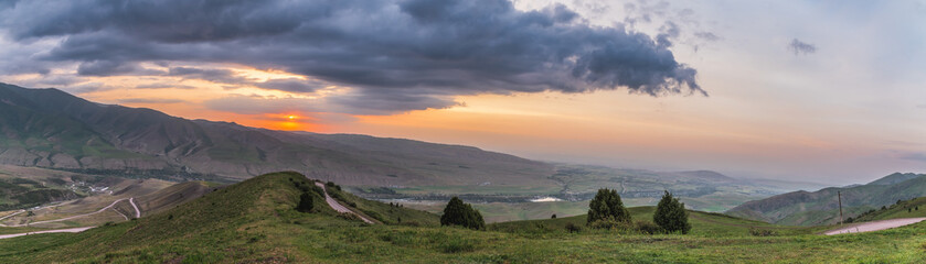 Panorama of winding mountain road stretching into sunset.