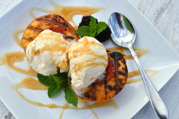 Grilled peaches topped with vanilla ice cream and caramel sauce drizzle. Easy summer picnic dessert. 
