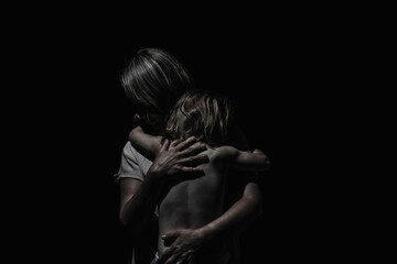 a girl hugs a child on a black background