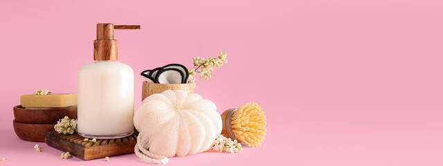 Bottle with liquid soap and bathing accessories on pink background with space for text