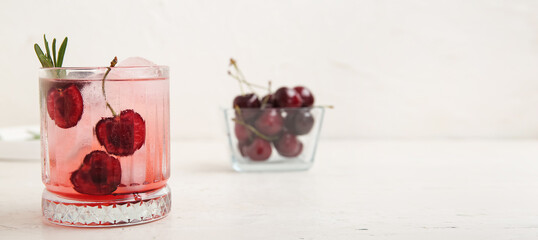 Glass of tasty cherry lemonade on light background with space for text