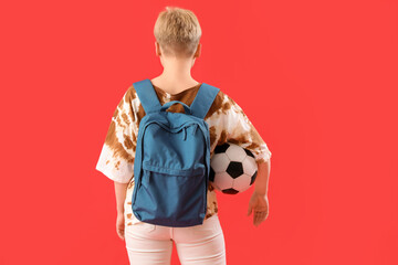 Female student with backpack and soccer ball on red background, back view