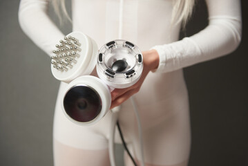 A woman showing the attachments of a slimming machine to cavitation, rf lifting and vacuum treatment