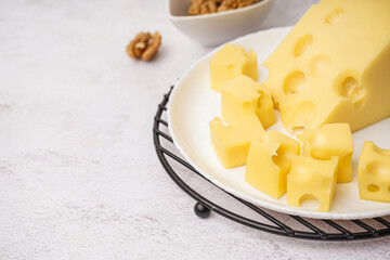 Stand and plate with pieces of Swiss cheese on white table