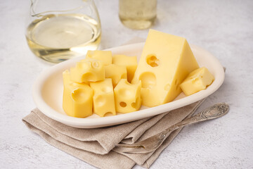 Plate with pieces of Swiss cheese on white table