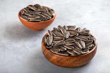 Black sunflower seeds in a bowl on bright background
