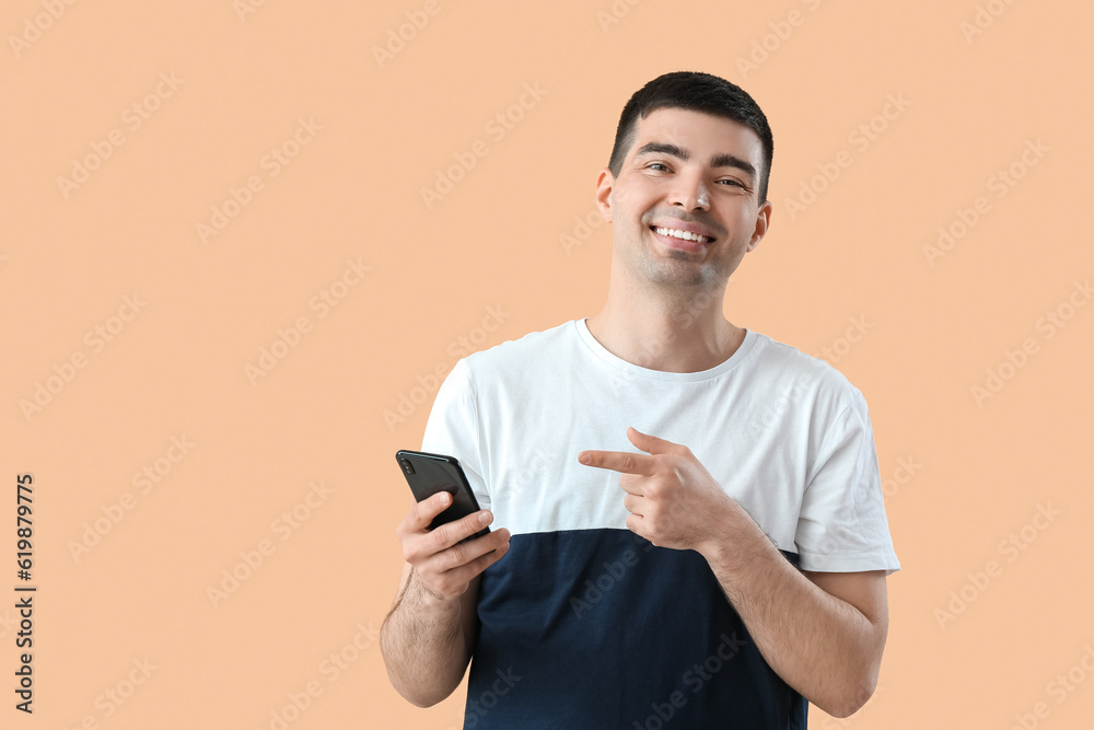 Poster Young man with smartphone on beige background