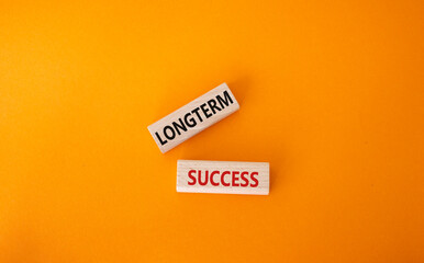 Longterm success symbol. Wooden blocks with words Longterm success. Beautiful orange background. Business and Longterm success concept. Copy space.