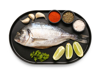 Tray of raw dorado fish with lime and spices on white background