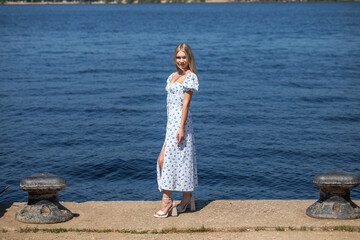 Portrait of a young beautiful blonde woman in a white summer dress