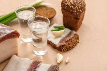 Shots with cold vodka and snacks on beige background