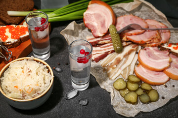 Shots with cold vodka and snacks on black background
