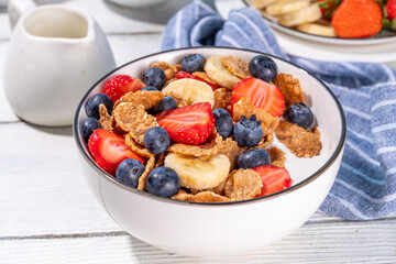 Healthy vitamin diet summer breakfast. Cereal Multigrain  flakes with yogurt or milk and strawberries, blueberries, on kitchen table copy space