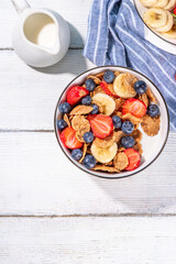 Healthy vitamin diet summer breakfast. Cereal Multigrain  flakes with yogurt or milk and strawberries, blueberries, on kitchen table copy space