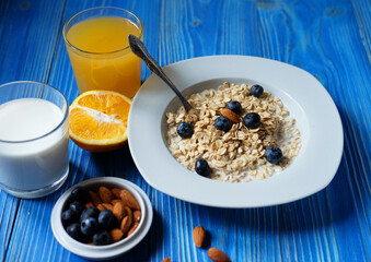 Healthy breakfast, food and diet concept - oatmeal with fresh berries on white plate with orange juice and milk