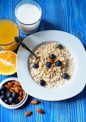 Healthy breakfast, food and diet concept - oatmeal with fresh berries on white plate with orange juice and milk