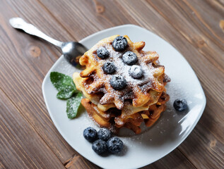 Waffles with blueberries and raspberries for breakfast over wooden table.