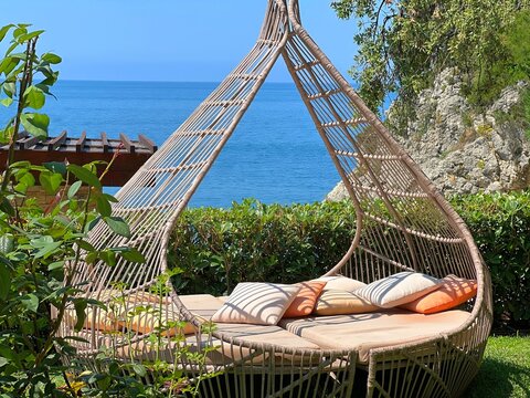 Cozy daybed lounger in Mediterranean garden patio on sea shore at summer.