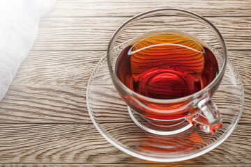 tea in cup of glass on a wooden background with gauze