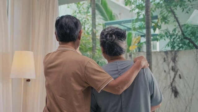 Back view of elderly couple looking at window while spending time together at home